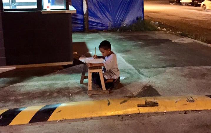 Il bambino filippino che fa i compiti alla luce di un lampione