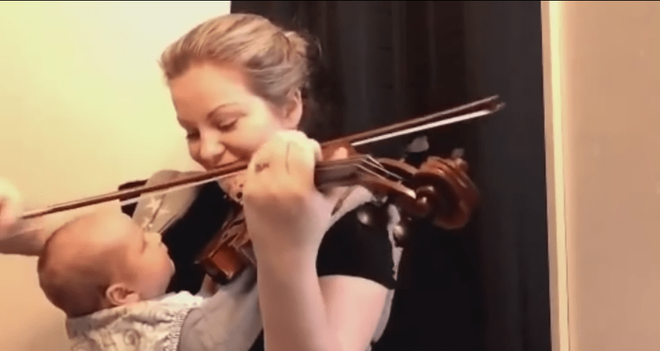 Mamma suona violino per neonato in braccio