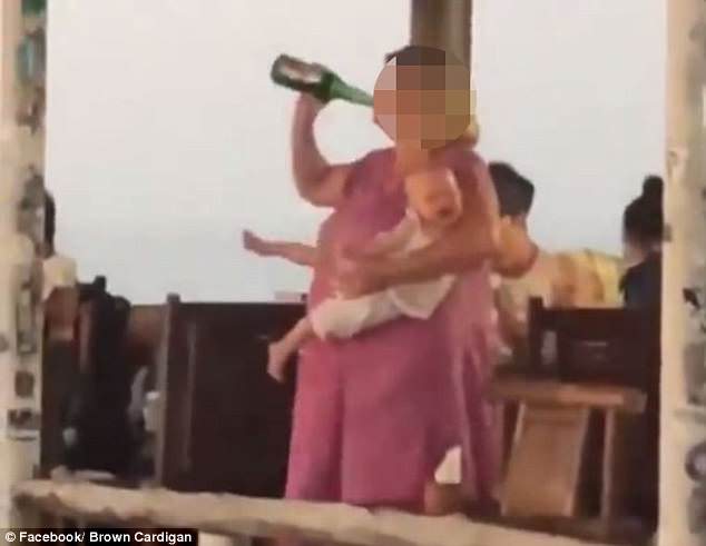 turista australiana beve birra con bambino in braccio
