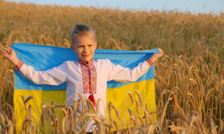 Bambino con la bandiera ucraina in un campo di grano