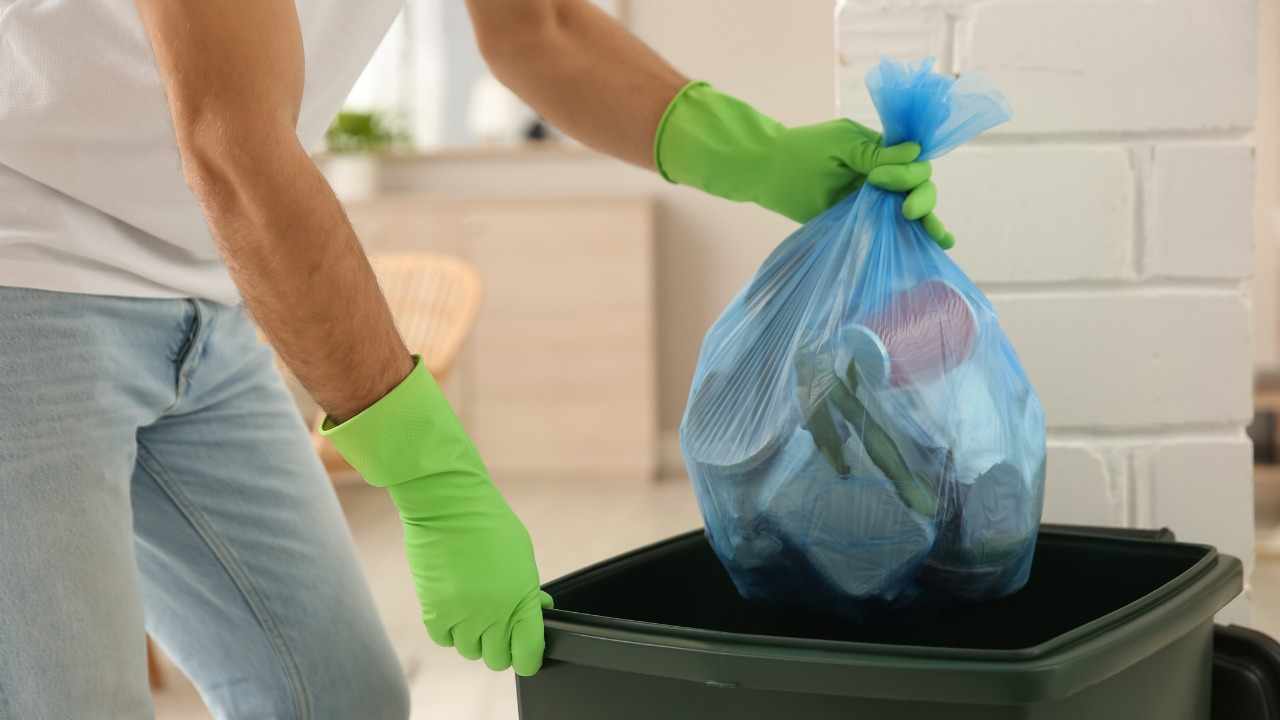 Uomo getta sacchetto nella spazzatura