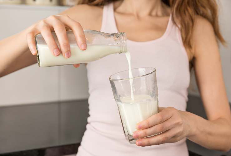 Donna che versa il latte nel bicchiere