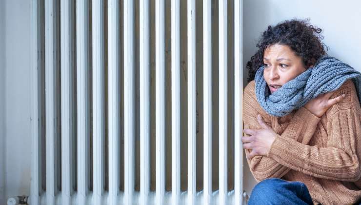Donna infreddolita vicino al termosifone 