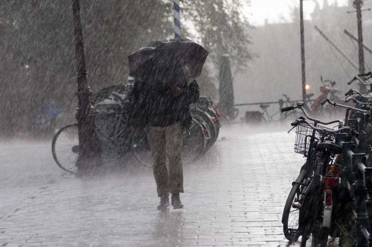 uomo con ombrello sotto forte pioggia