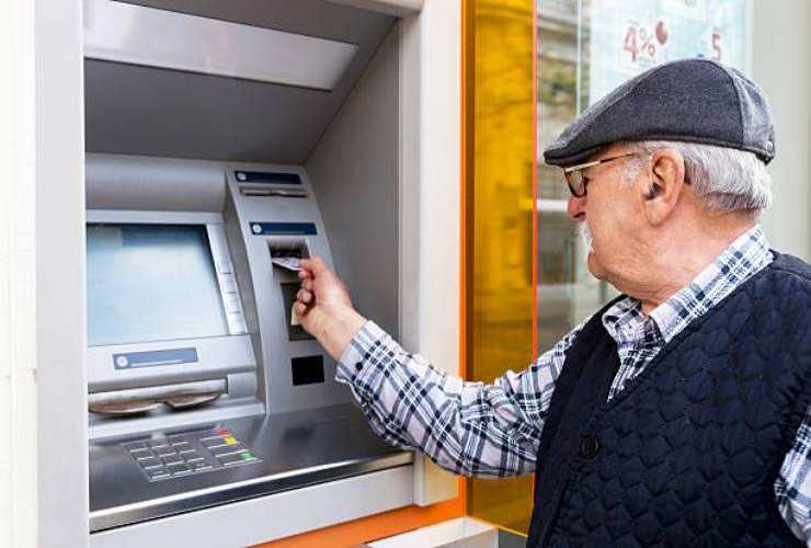 Anziano che preleva pensione al bancomat