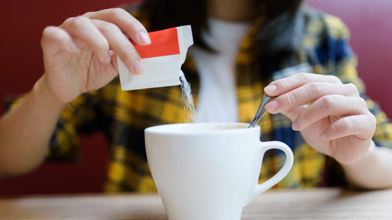 Donna che mette zucchero nel caffé