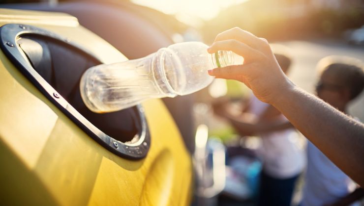 Bambini buttano bottiglie di plastica nei bidoni dedicati