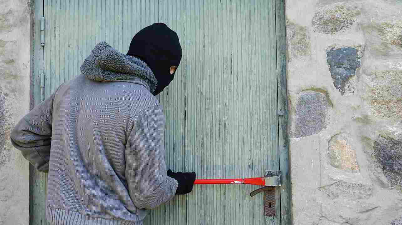 Ladro che scassina una porta