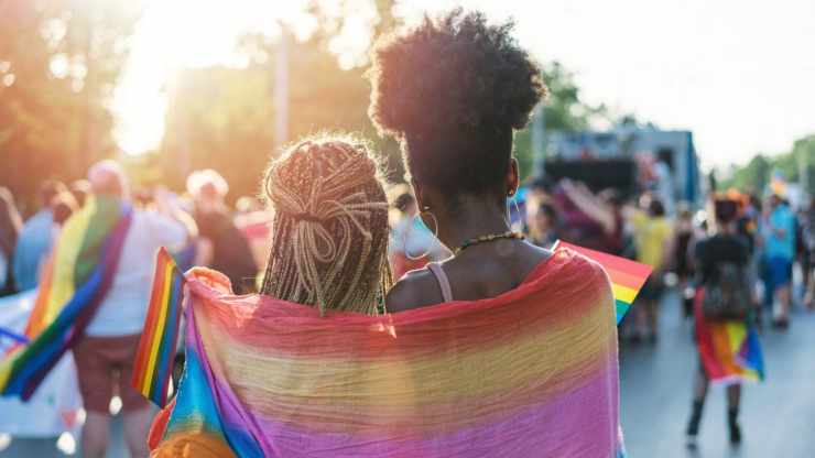 Ragazze avvolte da una bandiera arcobaleno