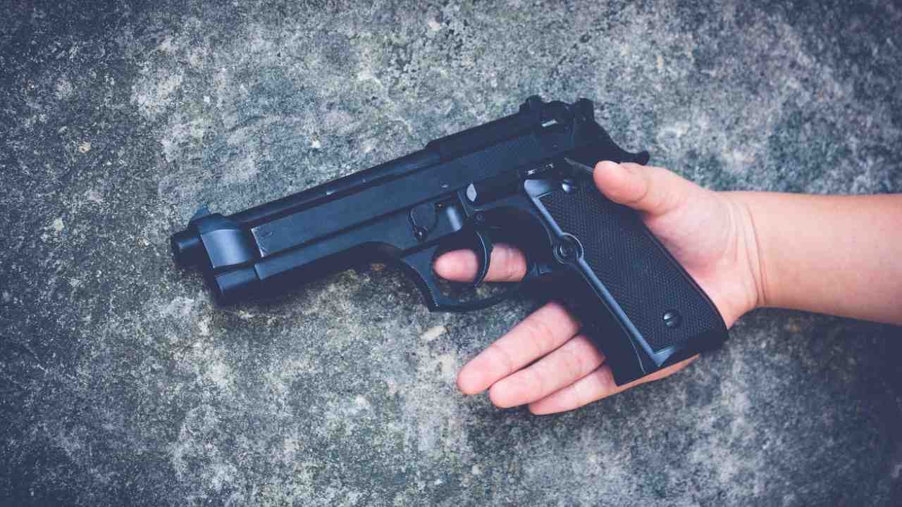 Mano di un bambino impugna arma