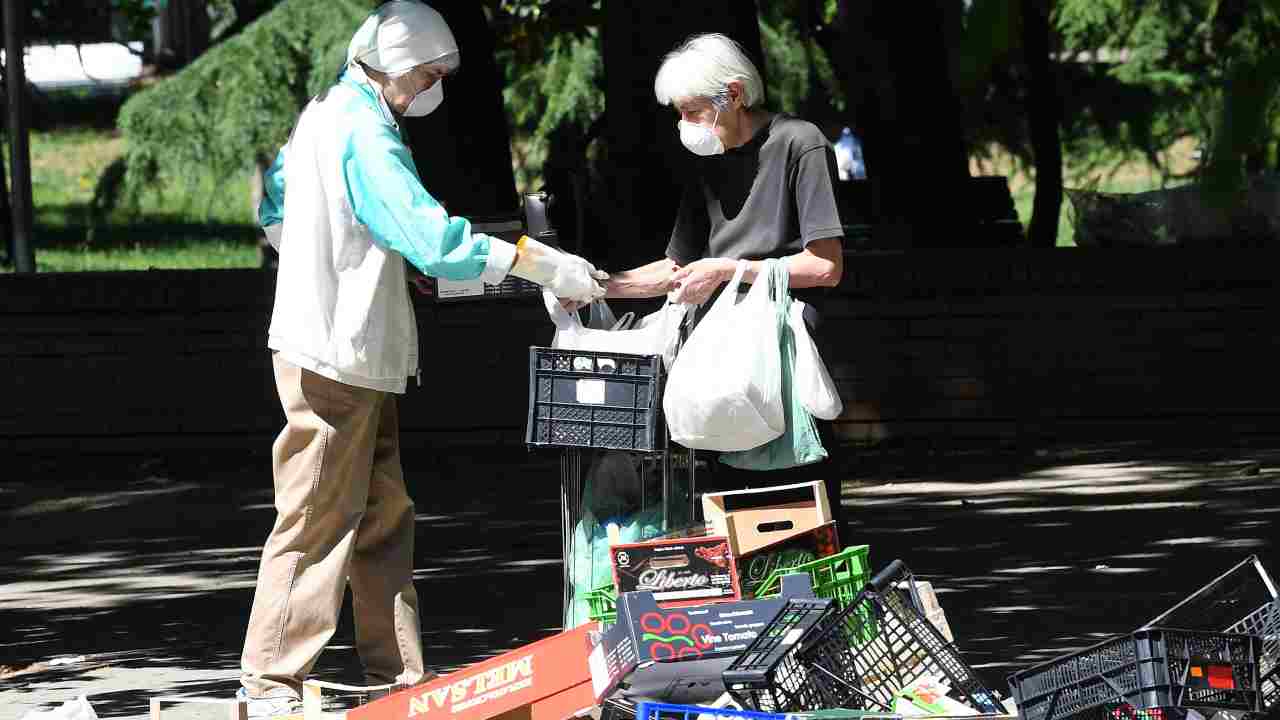 Due anziane cercano cibo tra i rifiuti